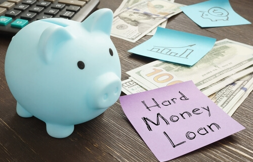 small piggy bank next to cash and a note that says hard money loans